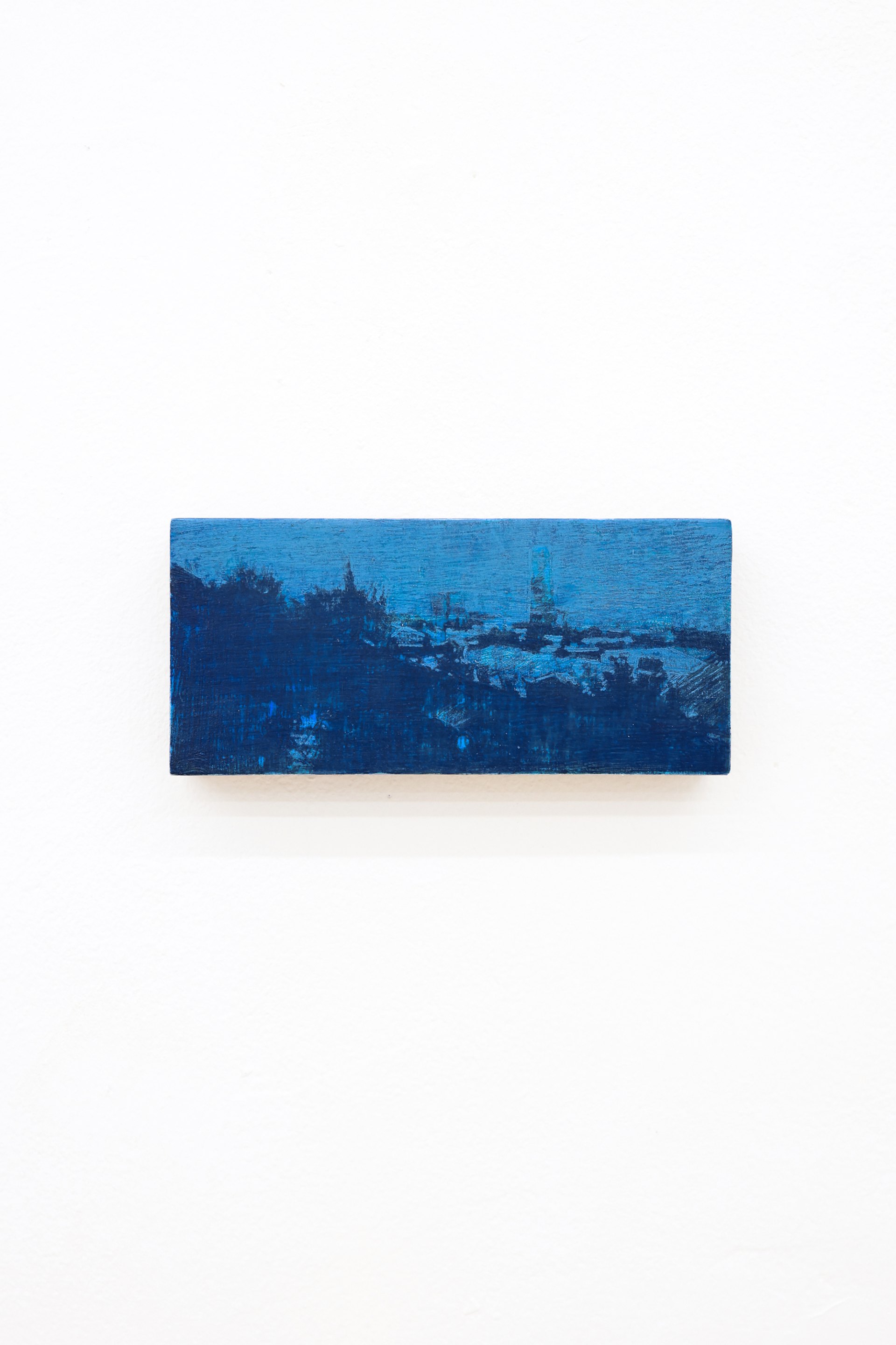 Mtatsminda Turn 12. Deep cobalt and midnight-blue nocturne on an oak block, a hillside of buildings and a slender tower beneath a luminous blue sky.