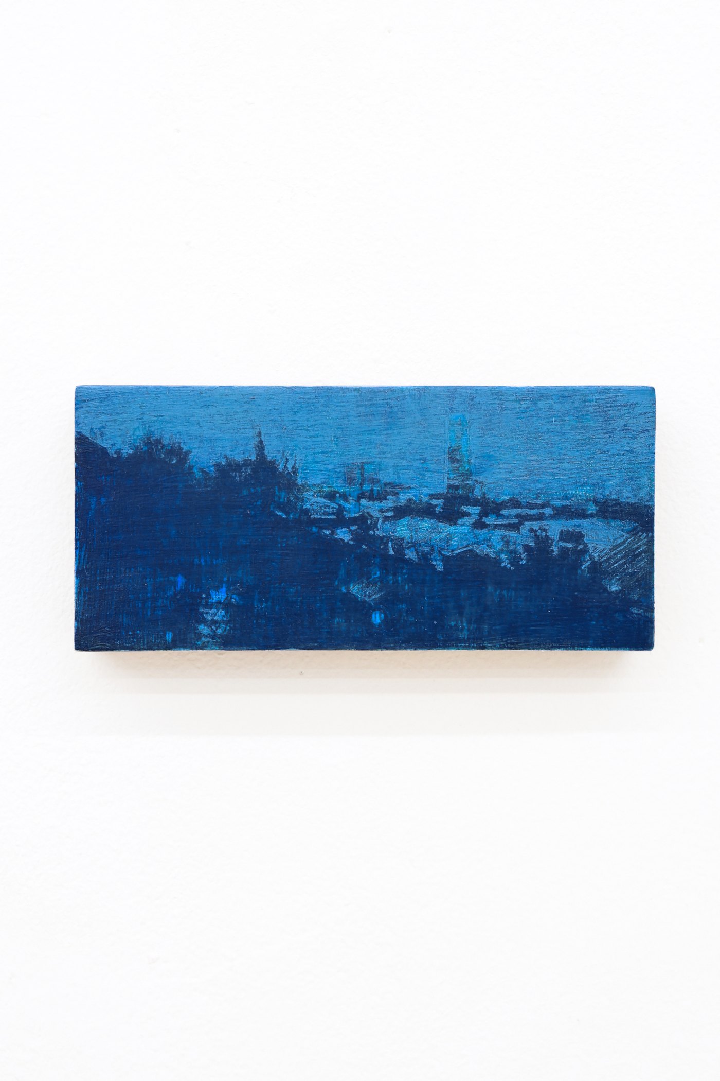 Mtatsminda Turn 12. Small horizontal night painting on an oak block, a cobalt-blue hillside cityscape with a faint tower.