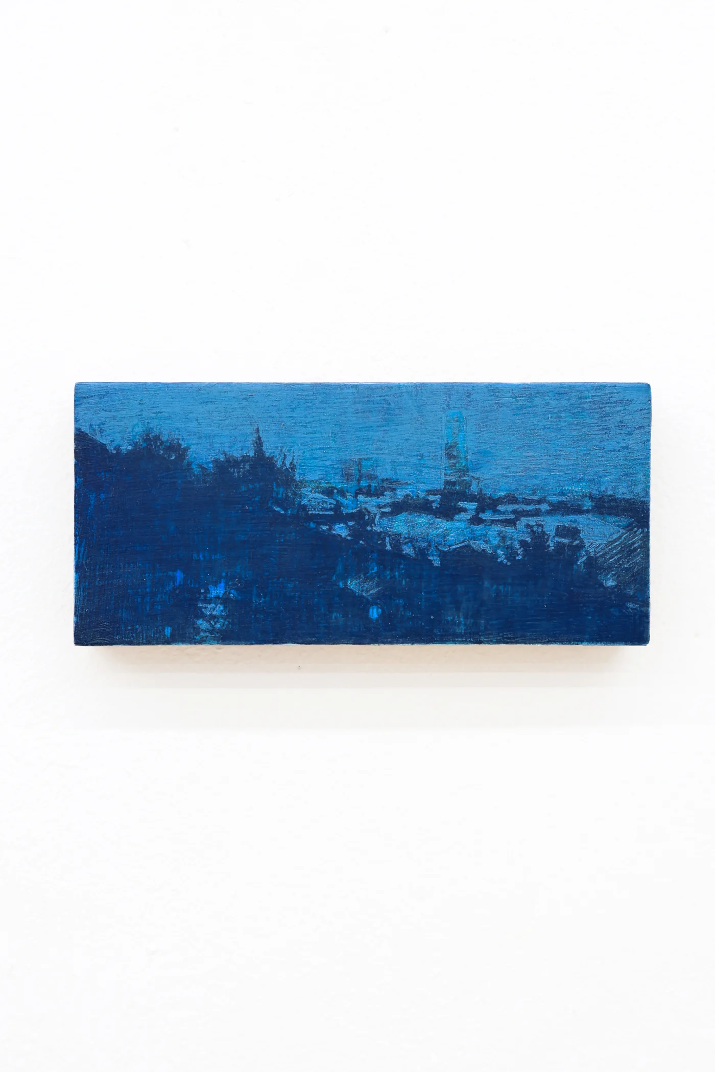 Mtatsminda Turn 12. Small horizontal night painting on an oak block, a cobalt-blue hillside cityscape with a faint tower.